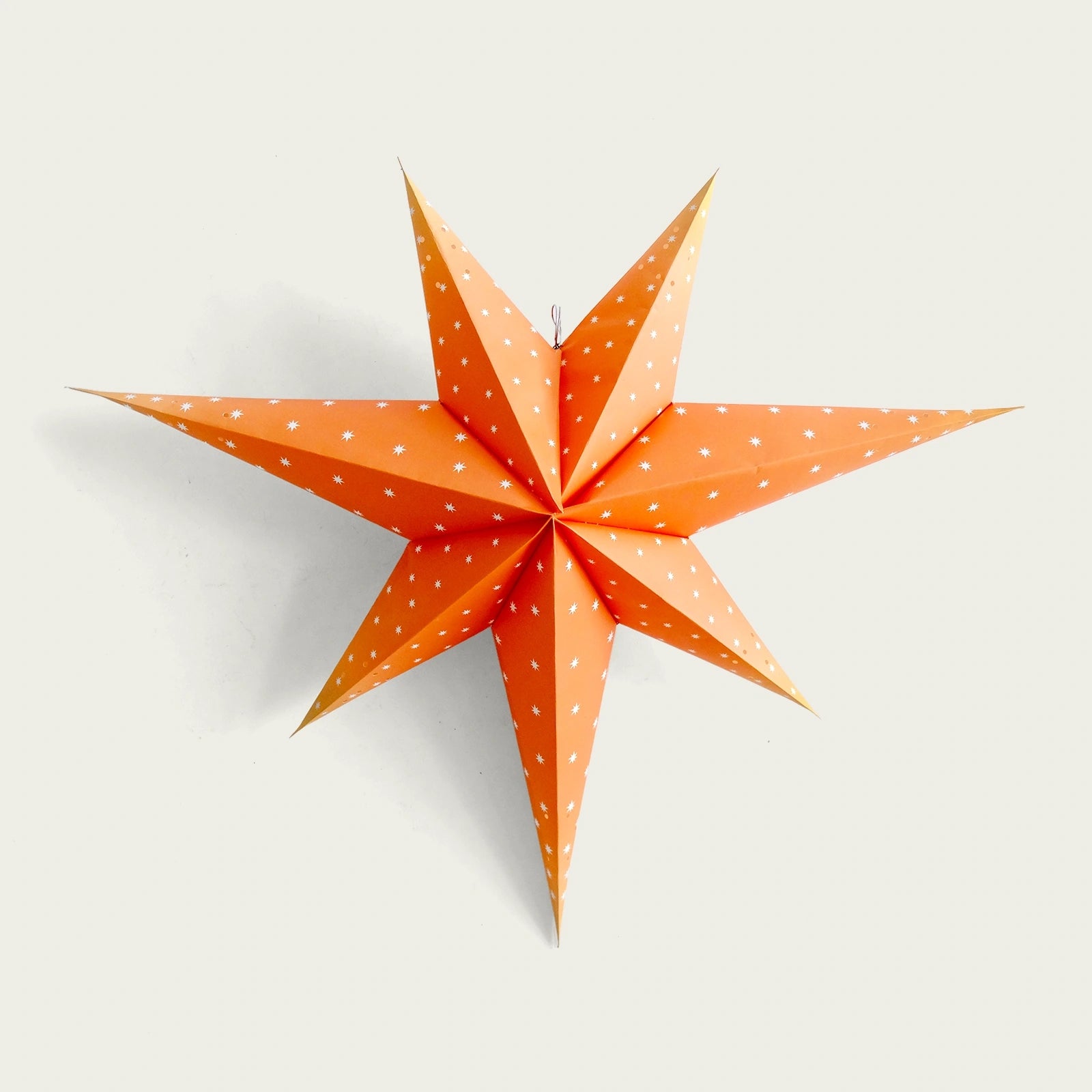 adventsstjarna-i-oranget-papper-med-sma-vita-stjarnor-i-pappret-som-dekoration-i-pappret-finns-diskreta-utstansade-hal-som-kan-slappa-igenom-ljus