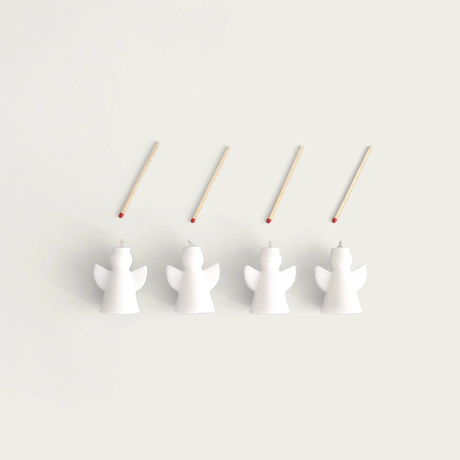 fyra-ljus-i-form-av-anglas-placerade-pa-rad-med-fyra-tandstickor-ovanfor