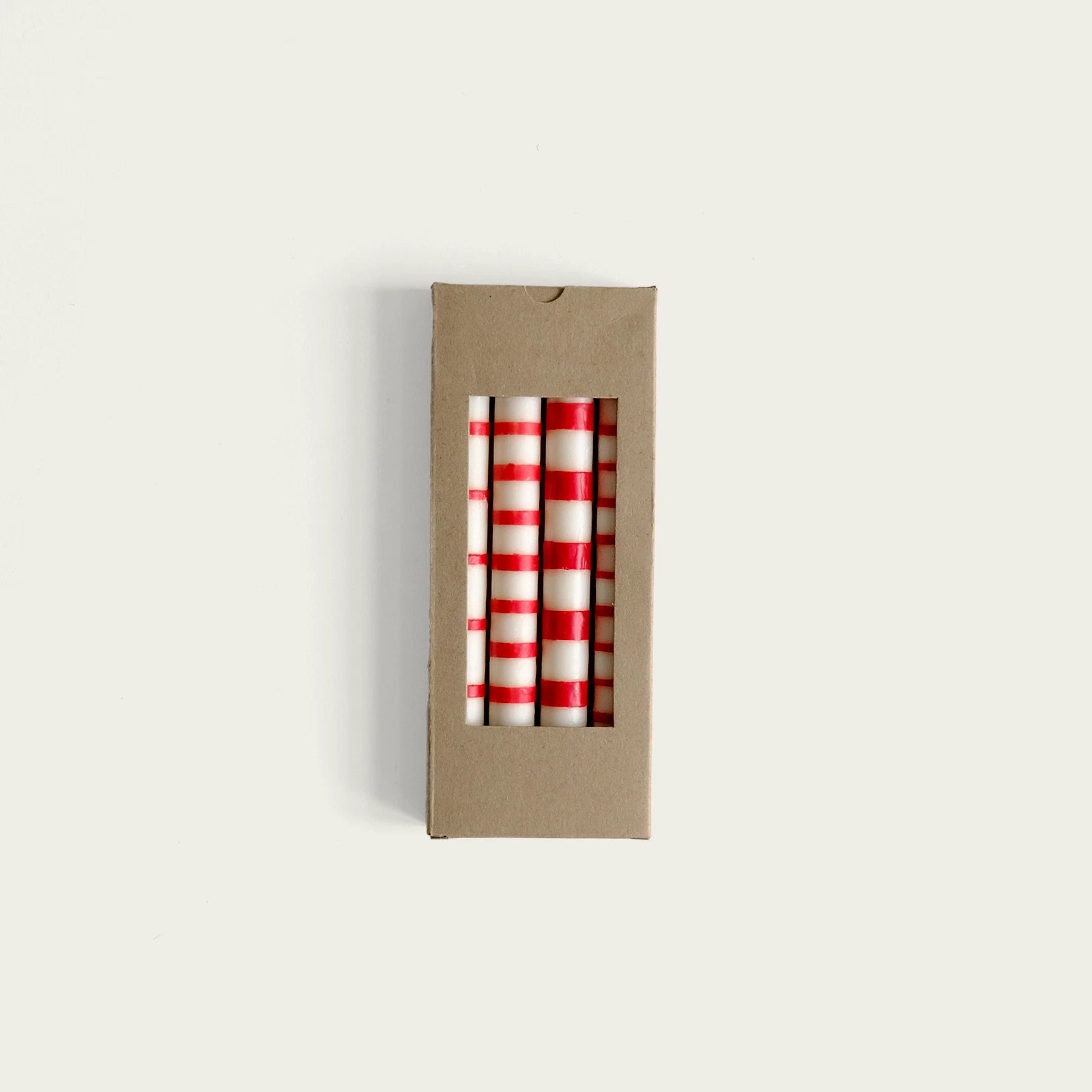fyra-vita-ljus-med-roda-rander-i-en-pappersforpackning
