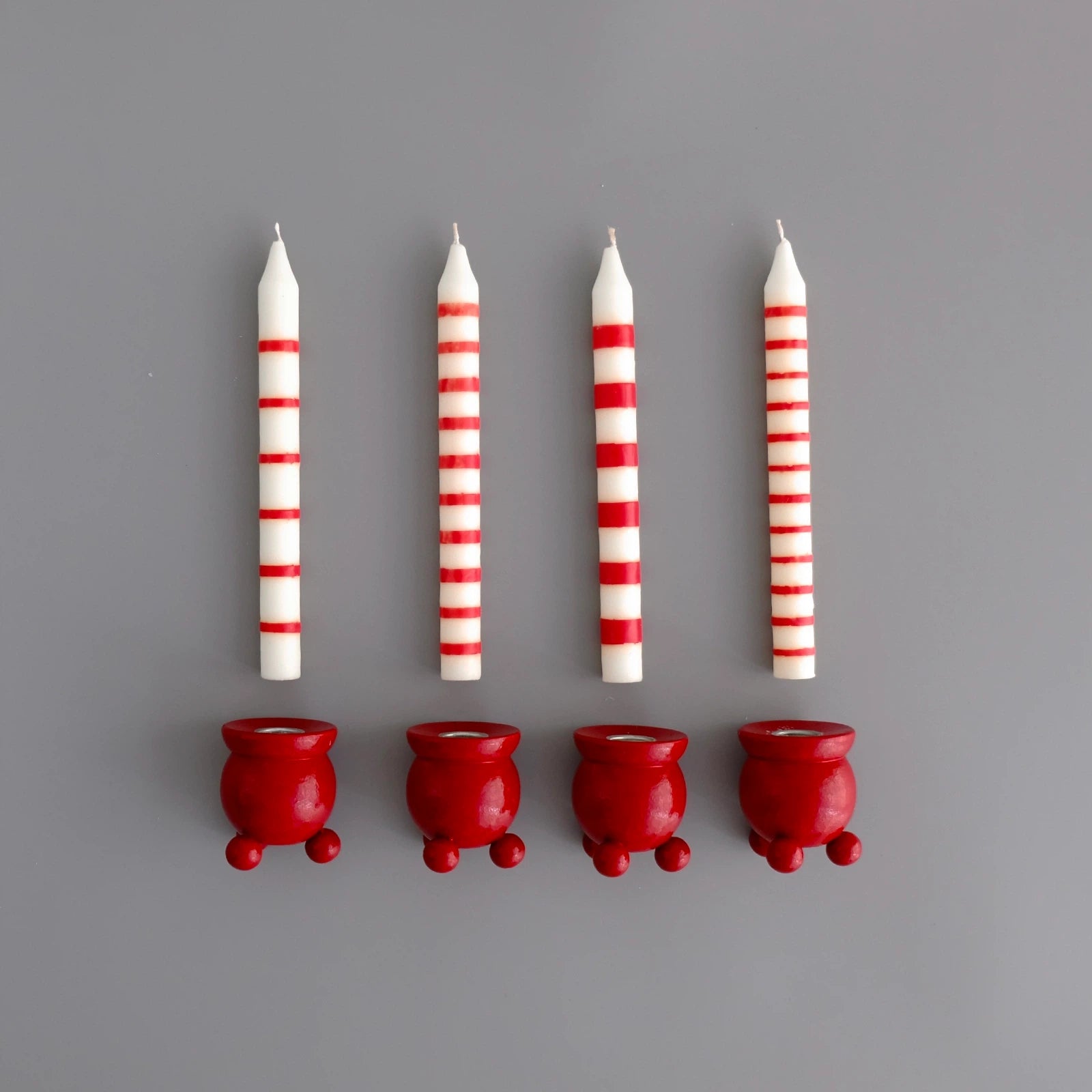 fyra-vita-ljus-med-roda-rander-pa-rad-under-varje-ljus-ar-det-en-rod-kulljusstake