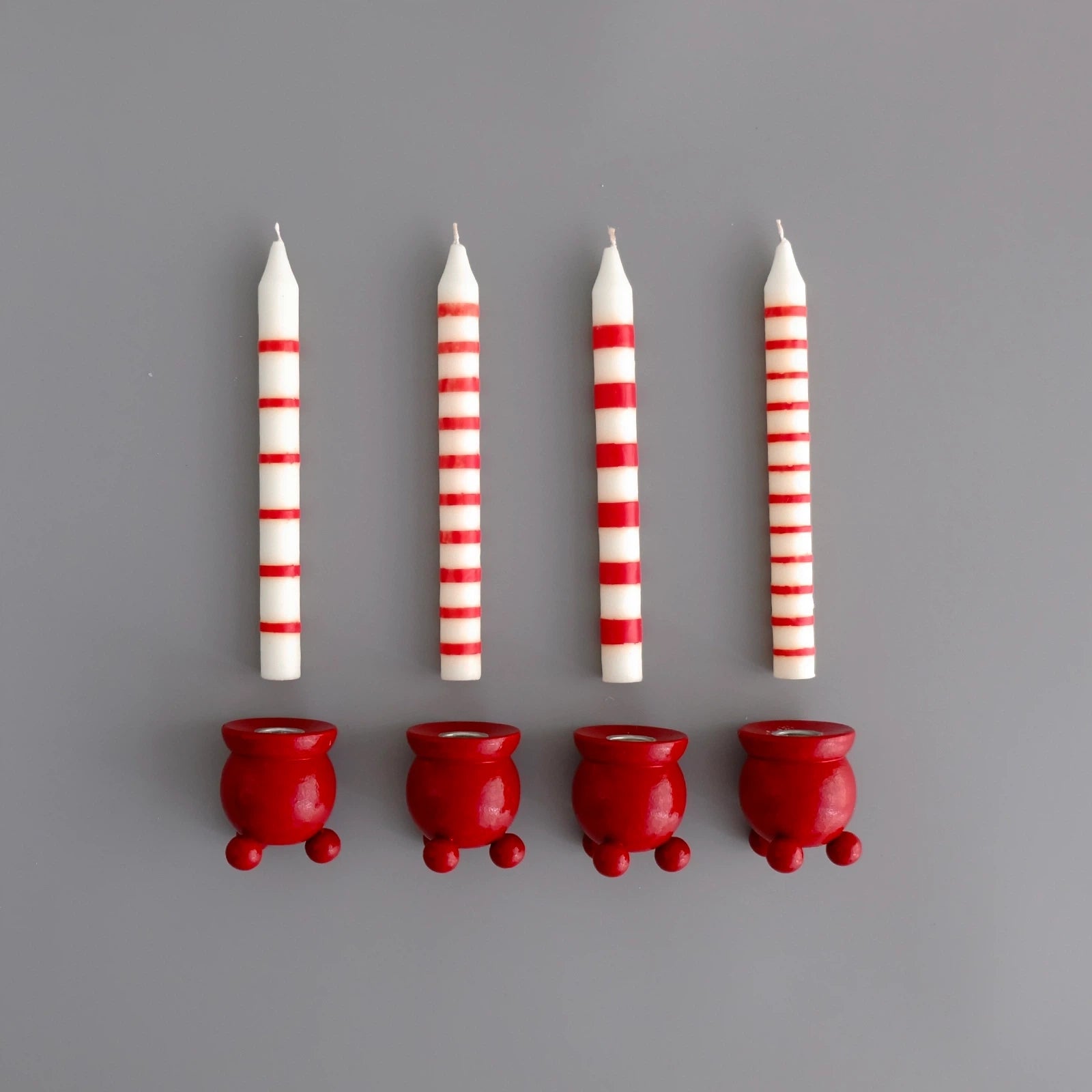 vit-och-rodrandiga-ljus-pa-rad-med-en-rod-kulljusstake-under-varje-ljus