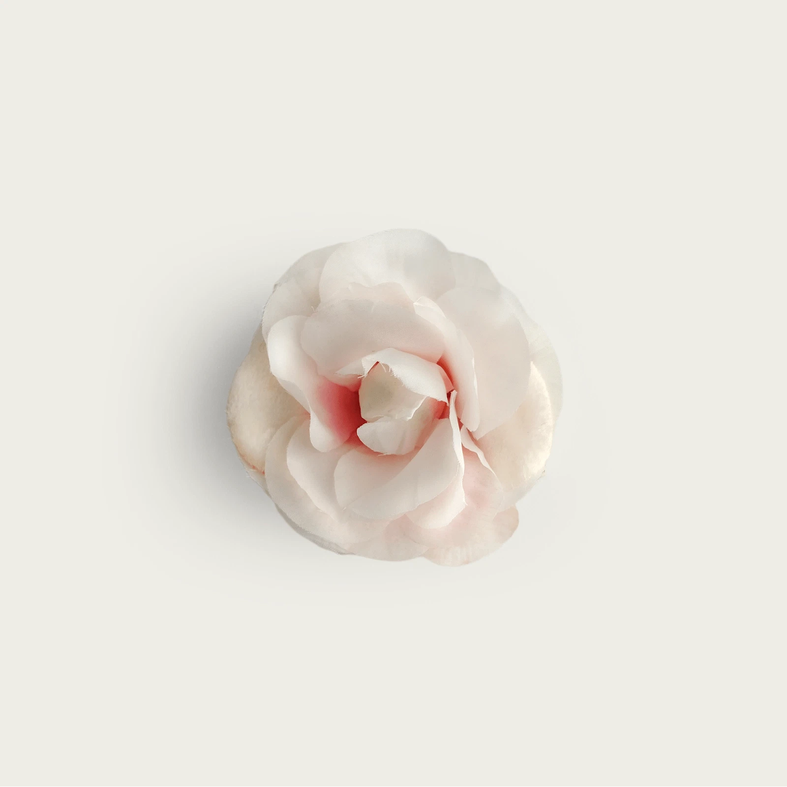 ljusrosa brosch som ar formad till en ros av aterbrukat sidentyg