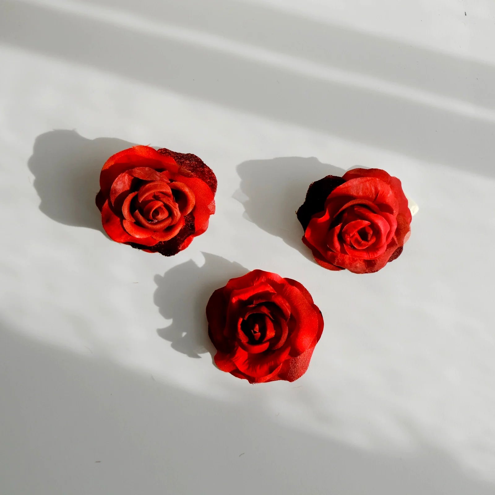 tre broscher som ar formade till roda rosor av aterbrukat sidentyg